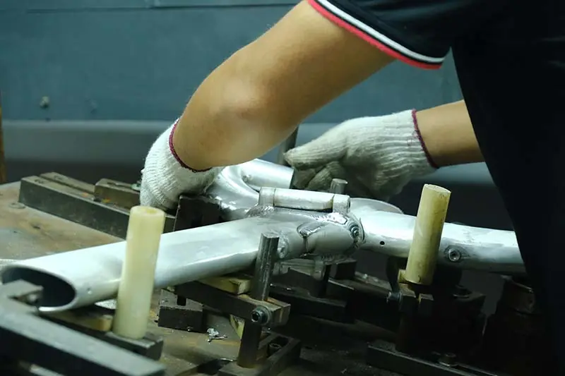 Welder working on an electric bike frame in a factory