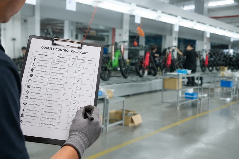 E-bike mass production consistency A quality control checklist next to an e-bike on an assembly line.