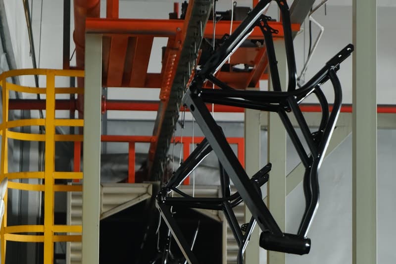 Quality Control for Matte Paint A factory worker inspecting a matte-painted e-bike frame under a strong light for imperfections.